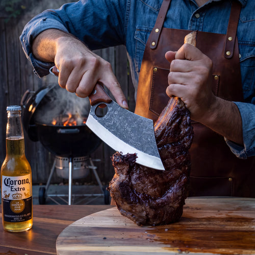 Découpe d'un tomahawk au couteau Dragotak devant un barbecue Weber